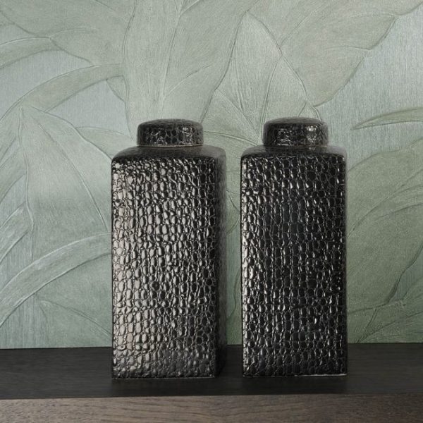 Twee zwarte, rechthoekige vazen met krokodillenstructuur staan voor een groene muurbekleding met groot bladmotief uit de Arte Monsoon Musa collectie.