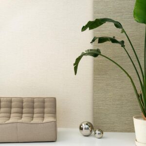 Moderne interieurhoek met Arte Pampas Sombra 73549 behang, een beige bank, grote groene plant en decoratieve metalen bollen.