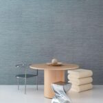 Moderne interieursetting met Arte Pampas Sombra 73550 behang, een ronde houten tafel, designstoelen en minimalistische decoratie.