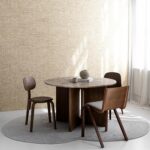 Moderne woonkamer met een ronde houten tafel, drie stoelen en Arte Pampas Cupula behang op de achtergrond.