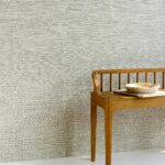 Houten bankje met keramische schaal tegen een muur met Arte Pampas Cupula-behang in lichtgrijze waaiervormige patronen.