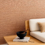 Moderne woonkamer met Arte Pampas Matiz 73526 behang, een lichte stoffen bank en houten bijzettafel met decoratieve accessoires.