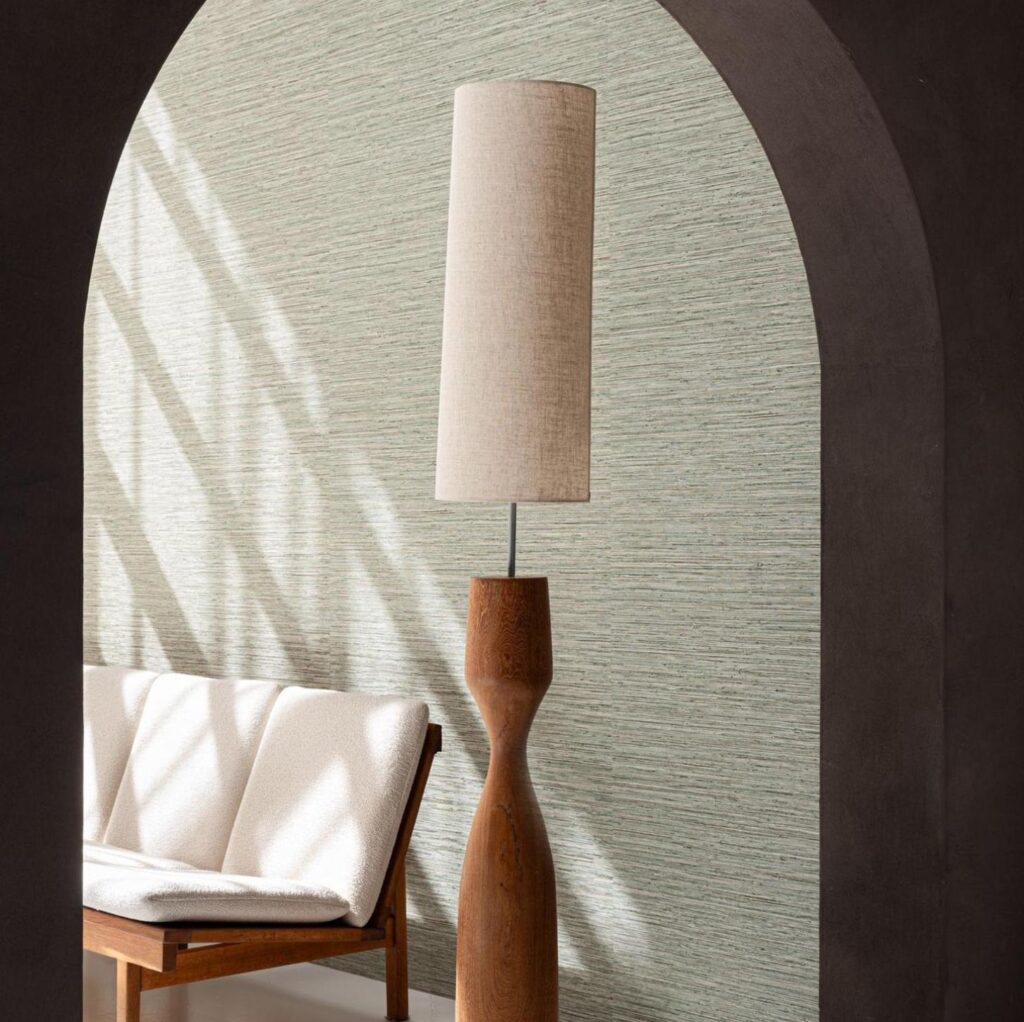 Moderne woonkamer met Arte Pampas Matiz 73532 behang, een houten vloerlamp en een retro bankje met witte bekleding.