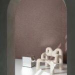 Moderne woonkamer met Arte Pampas Motas 73512 behang, een sculpturale witte fauteuil en een spiegelend kubusvormig bijzettafeltje.