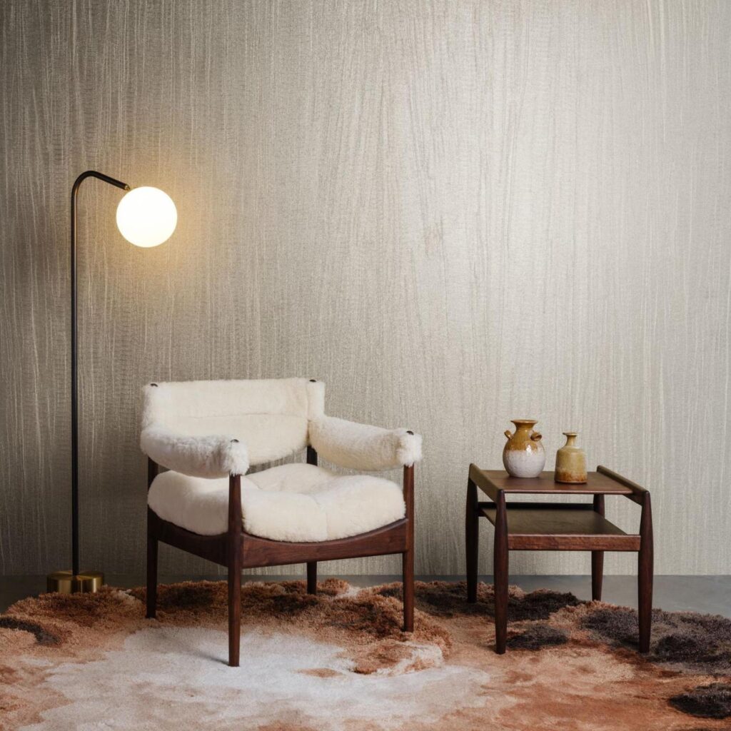 Scandinavisch interieur met Arte Pristine 23526A-behang, een zachte fauteuil, houten bijzettafel en vloerlamp op een textuurtapijt.
