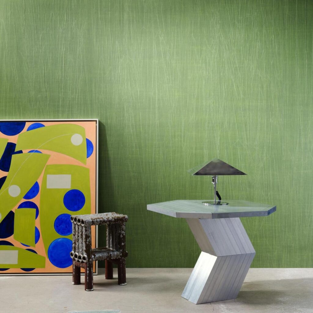 Moderne interieuroppstelling met Arte Pyxis 38015A groen behang, een abstract schilderij, een sculpturale stoel en een designlamp op een hoekige metalen tafel.