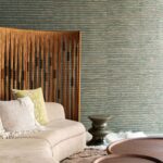 Moderne woonkamer met Arte Raphia behang, een beige bank, sierkussens en een houten kamerscherm.