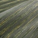 Close-up van het Arte Raphia behang met een geweven structuur in groentinten en natuurlijke vezels.