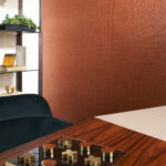 Moderne woonkamer met Arte Shimmer behang 40352 in koperkleur en luxe houten tafel met spel.