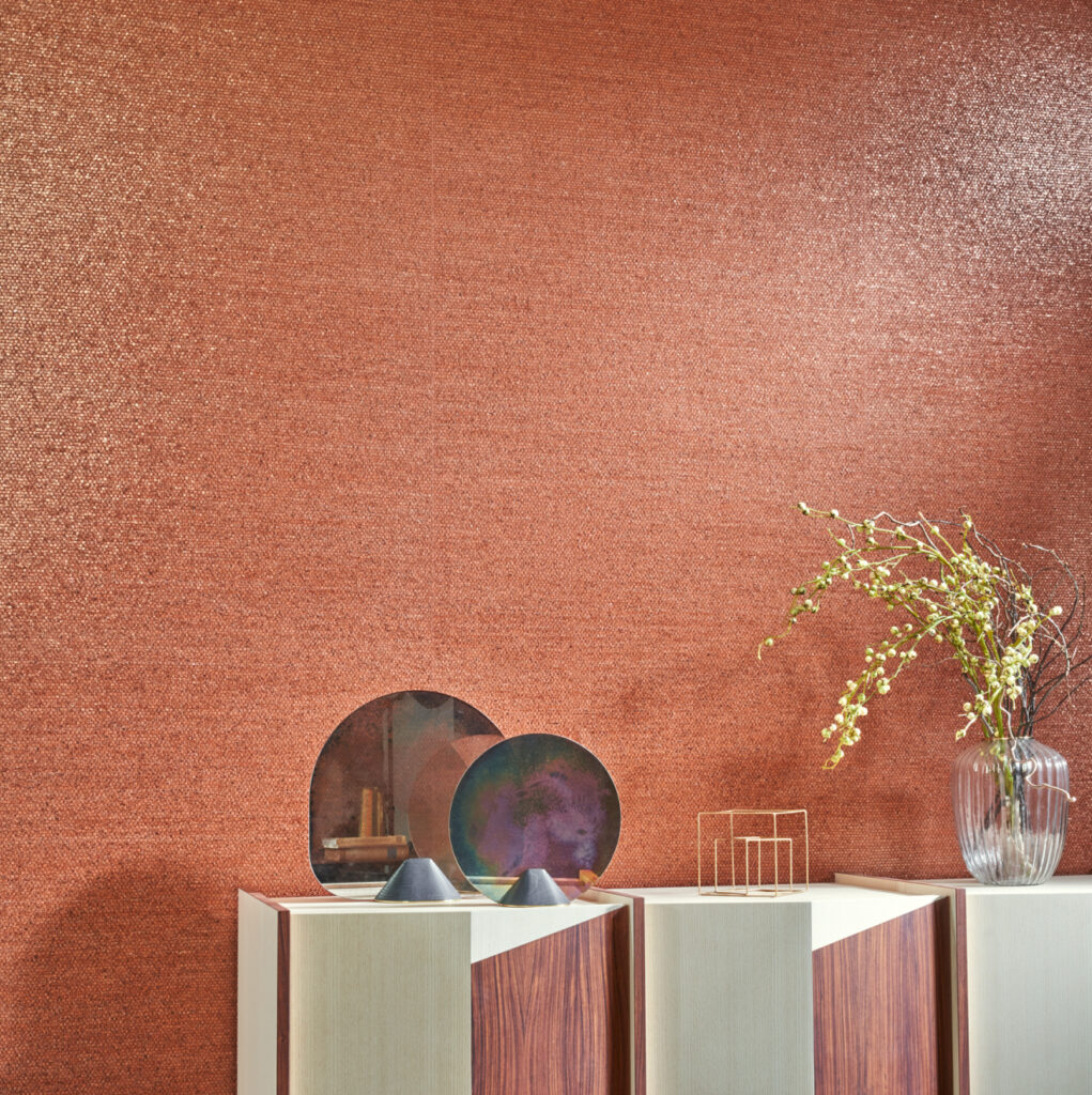Sfeervolle woonkamer met glanzend koperkleurig Arte Shimmer behang en moderne decoratie op een designkast.