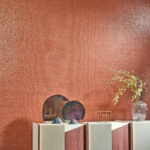 Sfeervolle woonkamer met glanzend koperkleurig Arte Shimmer behang en moderne decoratie op een designkast.