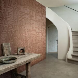 Sfeervolle hal met een decoratieve Arte Tali Sarana 60702 wandbekleding, een rustieke houten tafel en een moderne betonnen trap.