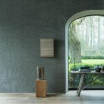 Sfeervolle interieurhoek met Arte Tali Sarana 60704 behang, houten accenten en uitzicht op een groene tuin.