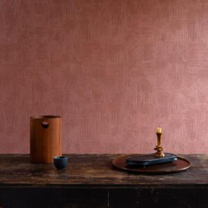 Sfeervolle interieursetting met Arte Tali Tamba 60728 behang in terracottatint en decoratieve objecten op een houten tafel.