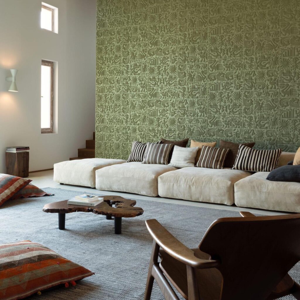 Woonkamer met beige loungebank, houten meubelen en een groene Arte-Terra Chimu 23903 muur met reliëfpatroon.