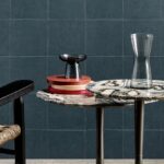 Moderne interieursetting met marmeren bijzettafels, glazen accessoires en een blauw getegelde Arte-Textura Campo 21040A muur.