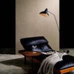 Luxe loungestoel met zwart lederen bekleding en houten tafeltje, geplaatst tegen een Arte-Textura Campo 21048A wandtegel.