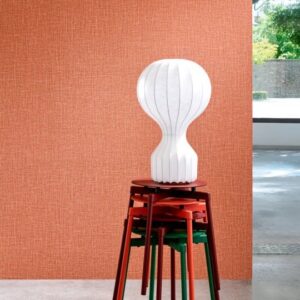 Witte designlamp opgestapeld op gekleurde krukken voor een oranje Arte-Textura Gioco wandbekleding in de kleur ginger.