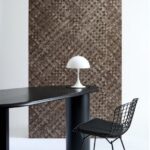 Moderne interieursetting met Arte-Textura Pandan behang, een zwarte designstoel, ovale zwarte tafel en een witte tafellamp.