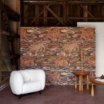 Sfeervolle interieurhoek met Arte Tigris behang uit de Gitane collectie, met een patroon van tijgers en golvende lijnen in warme tinten.