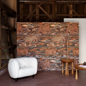 Sfeervolle interieurhoek met Arte Tigris behang uit de Gitane collectie, met een patroon van tijgers en golvende lijnen in warme tinten.