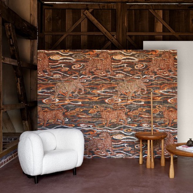Sfeervolle interieurhoek met Arte Tigris behang uit de Gitane collectie, met een patroon van tijgers en golvende lijnen in warme tinten.