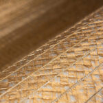 Detailopname van het Arte Twill behang 40330 met een glanzende, goudkleurige geweven textuur.