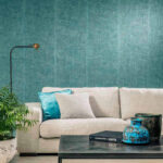 Moderne woonkamer met lichtbeige bank, turquoise Arte Uno behang en decoratieve accessoires op een salontafel.
