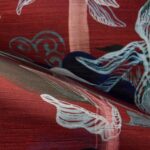 Detail van Arte-behang Alaya Saranda 11540 met een rood patroon en sierlijke florale illustraties.