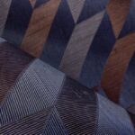 Close-up van Arte-behang Arrow met een grafisch patroon van schuine lijnen en geometrische vormen in blauw- en bruintinten.