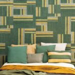 Slaapkamer met kleurrijk beddengoed en grafisch groen-geel Arte-behang uit de Atelier Boro AT71 collectie.