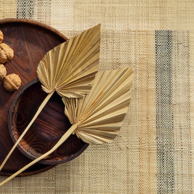 Twee gedroogde palmbladeren en walnoten in een houten schaal op Arte-behang Atelier Boro AT73.