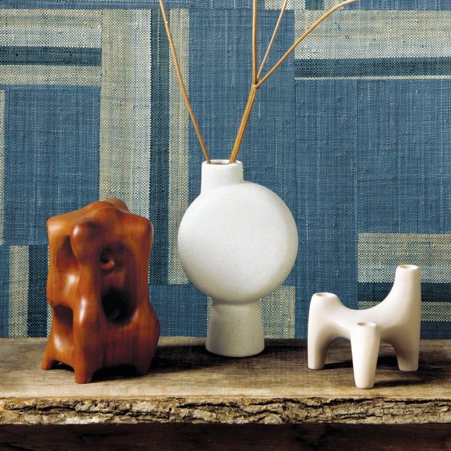 Decoratieve objecten op een houten plank voor een blauw Arte Atelier Boro AT74 behang met grafisch patroon.