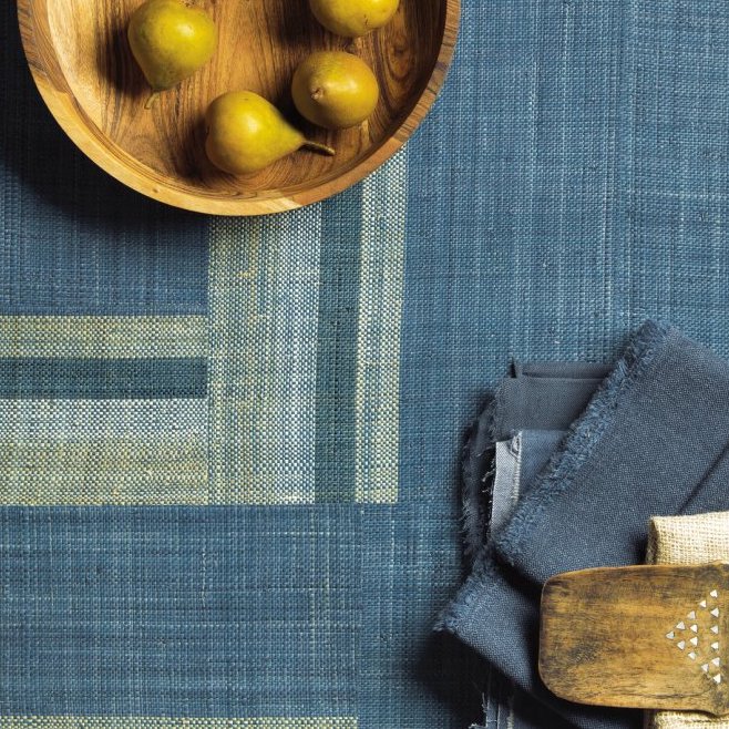 Houten schaal met peren op blauw Arte behang uit de Atelier Boro AT74 collectie, met daarnaast stapels stofstaaltjes.