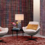 Stijlvol interieur met kleurrijk Arte Atelier Extravaganza behang (AT61 en AT62), moderne stoelen en een lamp op een bijzettafel.