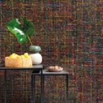 Moderne woonkamer met Arte behang Mademoiselle Tweed AT-32 en een decoratief tafeltje met fruit, nootjes en een vaas met blad.