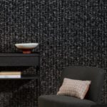 Moderne interieurhoek met Arte Atelier Mademoiselle Tweed AT-33 behang, zwarte bijzettafel en grijze fauteuil met geruit kussen.