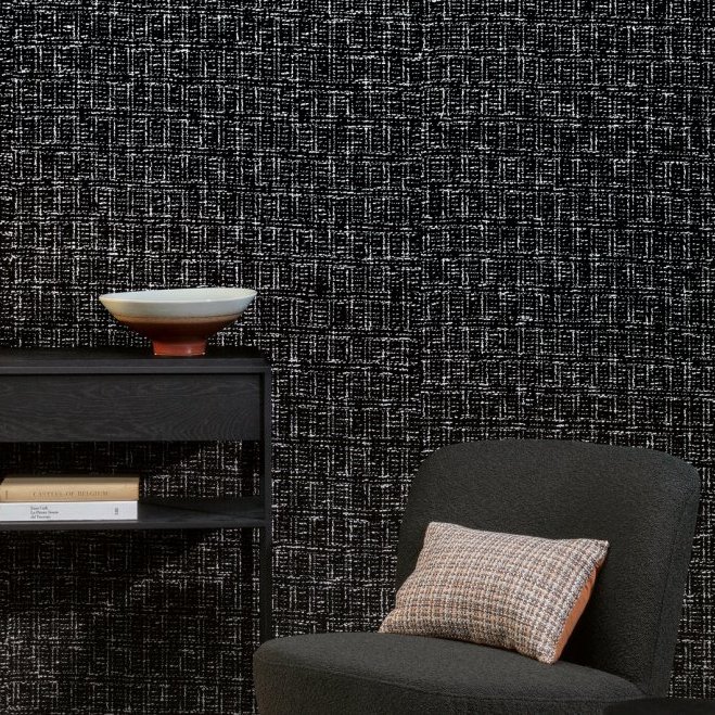 Moderne interieurhoek met Arte Atelier Mademoiselle Tweed AT-33 behang, zwarte bijzettafel en grijze fauteuil met geruit kussen.