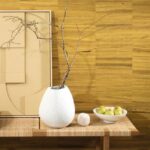 Houten wand met Arte-behang Atelier Naturally Beautiful AT-24, voor een tafel met een witte vaas, tak, schaal met peren en abstract kunstwerk.