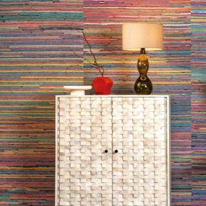 Witte kast met mozaïekpatroon voor kleurrijk gestreept Arte Atelier Rainbow Raj-behang, met een lamp en decoratieobjecten erbovenop.
