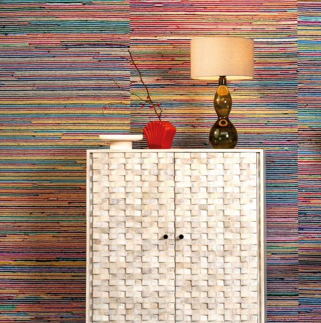 Witte kast met mozaïekpatroon voor kleurrijk gestreept Arte Atelier Rainbow Raj-behang, met een lamp en decoratieobjecten erbovenop.