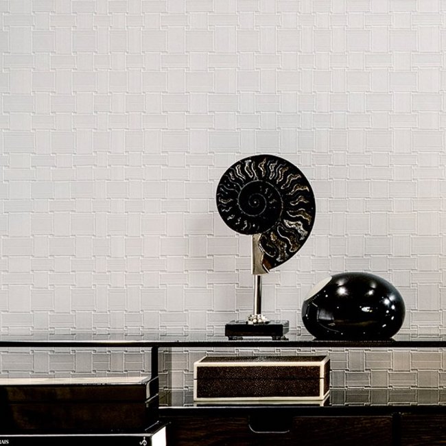 Moderne interieursetting met Arte behang Avalon Weave als achtergrond en decoratieve objecten op een glazen tafel.