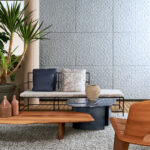 Moderne zithoek met Arte behang Babylon Adobe 97033 op de achtergrond en stijlvolle houten en metalen meubels.
