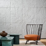 Designstoel en moderne bijzettafels voor een wand met wit reliëfbehang uit de Arte Babylon Between Rivers 97002 collectie.