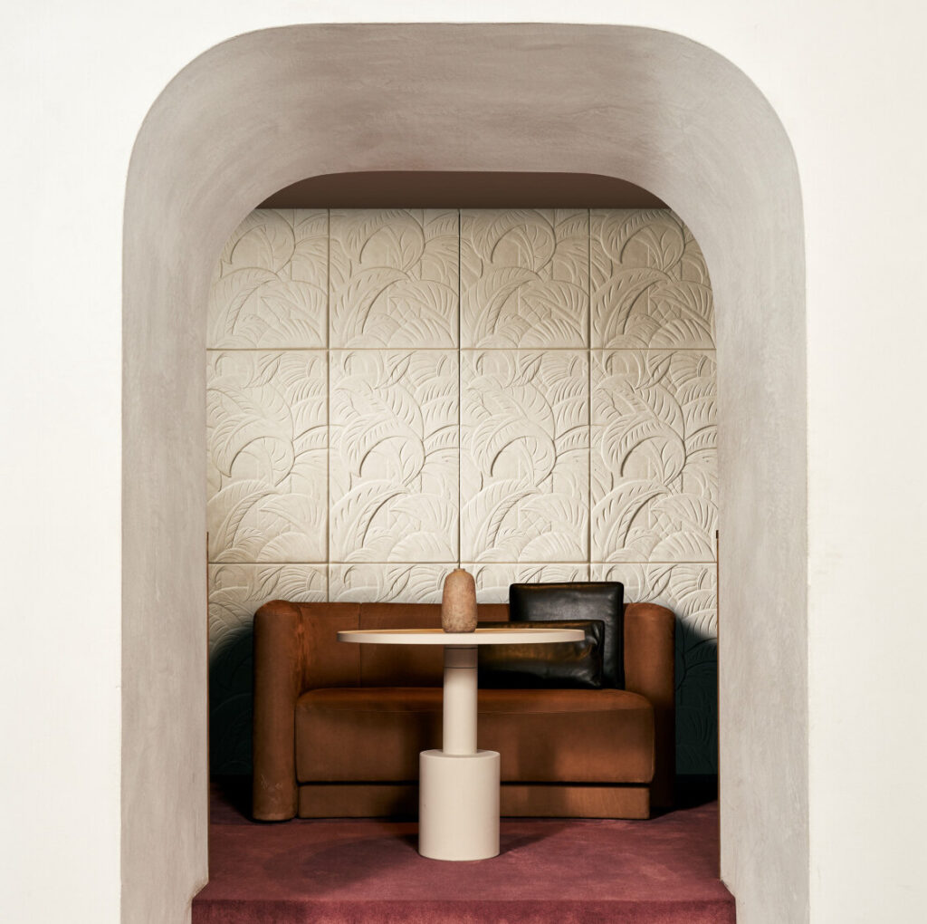Nis met een bruine bank, ronde tafel en Arte-behang Babylon Medjoul met reliëfpatroon op de achterwand.