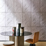 Moderne eetkamer met Babylon Medjoul behang van Arte met een palmbladreliëf, ronde tafel en decoratieve vazen.