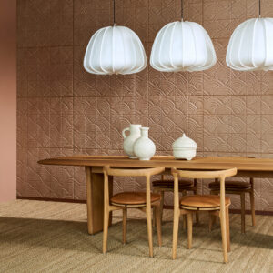 Moderne eetkamer met Arte Babylon behang in terracottatint, houten meubelen en drie witte hanglampen.