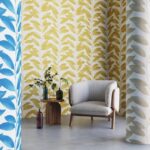 Moderne zithoek met Arte-behang Blooming Marvellous met geel bladpatroon en een beige fauteuil.