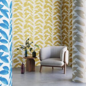 Moderne zithoek met Arte-behang Blooming Marvellous met geel bladpatroon en een beige fauteuil.