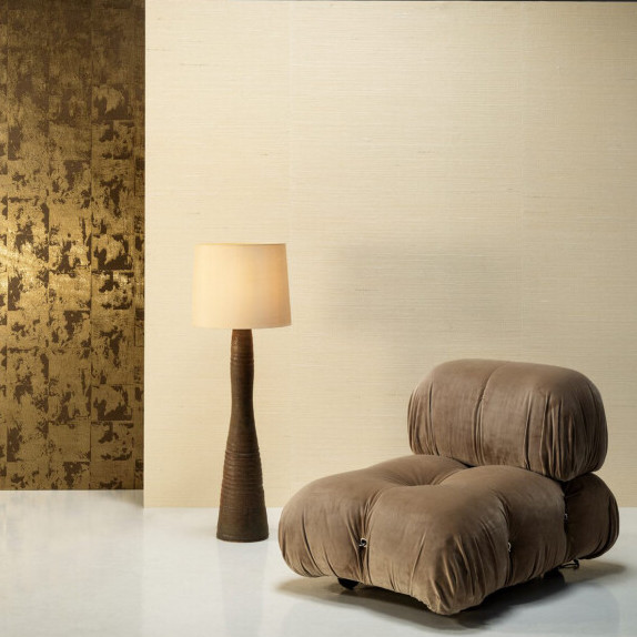 Moderne zithoek met een bruine designfauteuil, een staande lamp en Arte Boutique behang met goud en beige accenten.